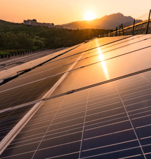 solar panels on roof with sun setting in the background behind the mountain